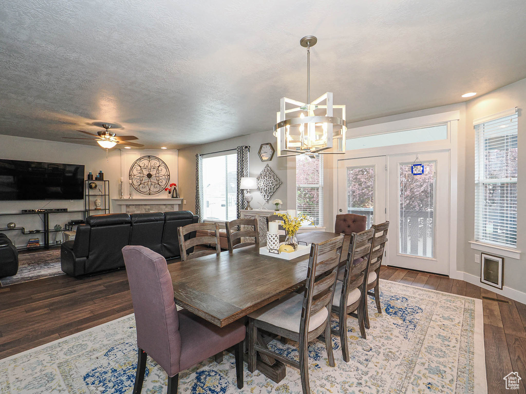 Dining area with a textured ceiling, hardwood / wood-style flooring, baseboards, ceiling fan with notable chandelier, and recessed lighting