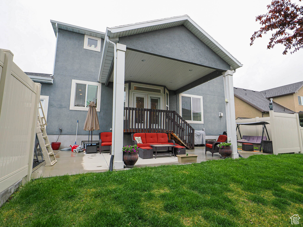 Back of property with a yard, an outdoor living space, a patio area, and stucco siding