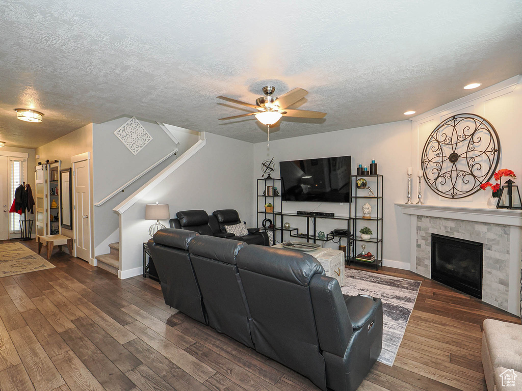 Living room with stairs, baseboards, dark wood-type flooring, a textured ceiling, and a ceiling fan
