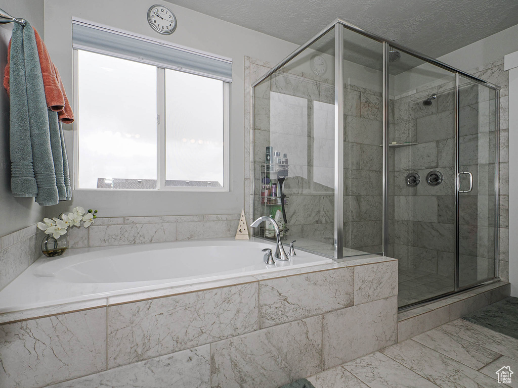 Bathroom featuring a garden tub, marble finish floor, and a stall shower