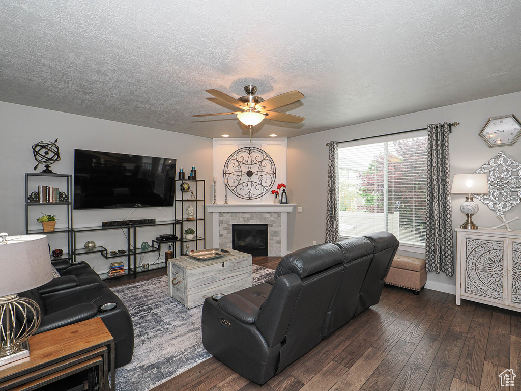 Living room with dark wood-style flooring, ceiling fan, and a textured ceiling