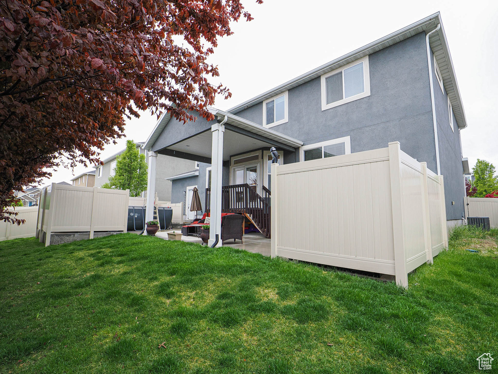 Back of property featuring a lawn, fence, and stucco siding