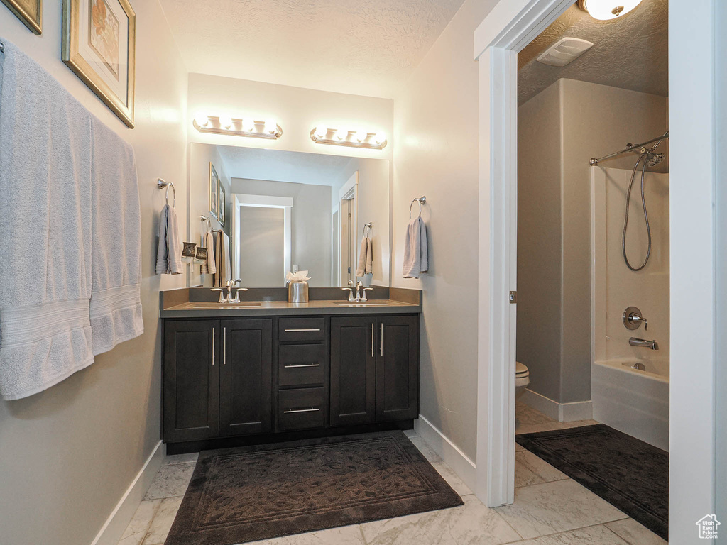 Bathroom with a sink, baseboards, double vanity, and visible vents