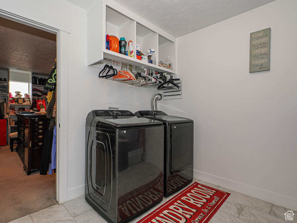 Laundry area with laundry area, a textured ceiling, baseboards, bar area, and washer and clothes dryer