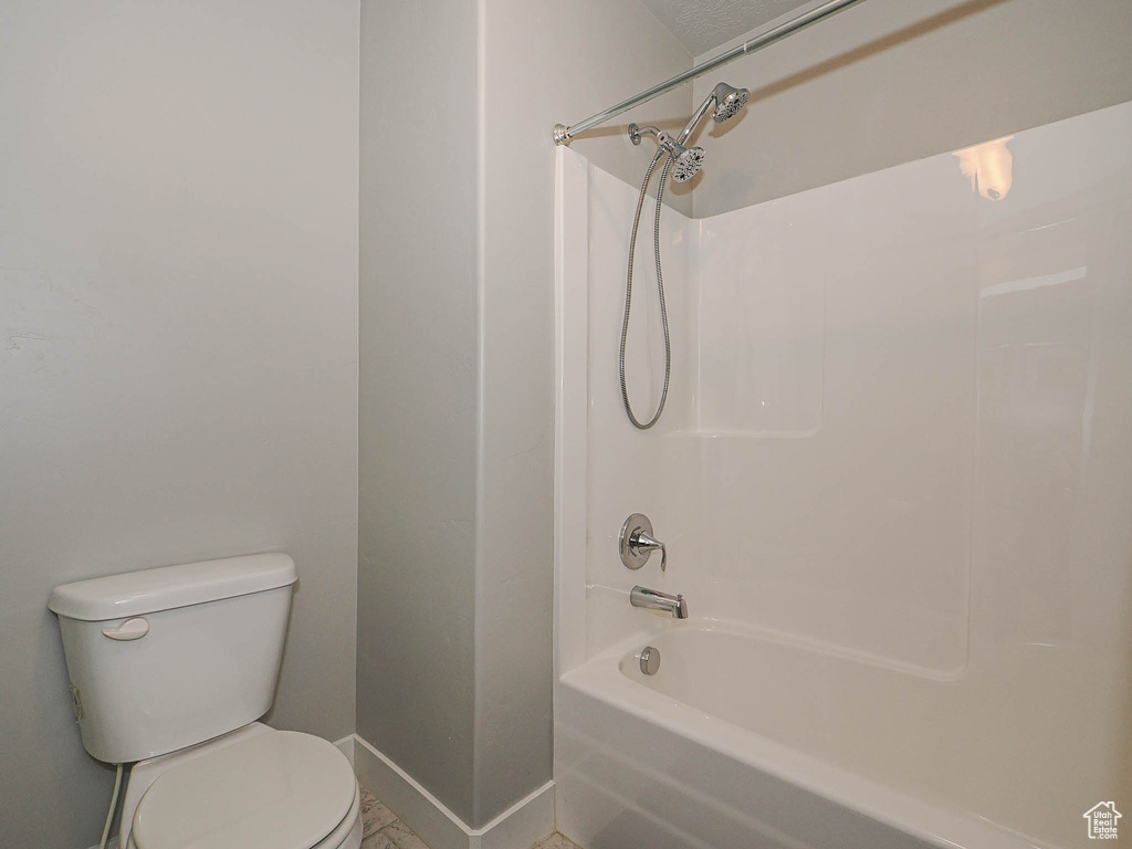 Bathroom featuring baseboards, bathtub / shower combination, and toilet
