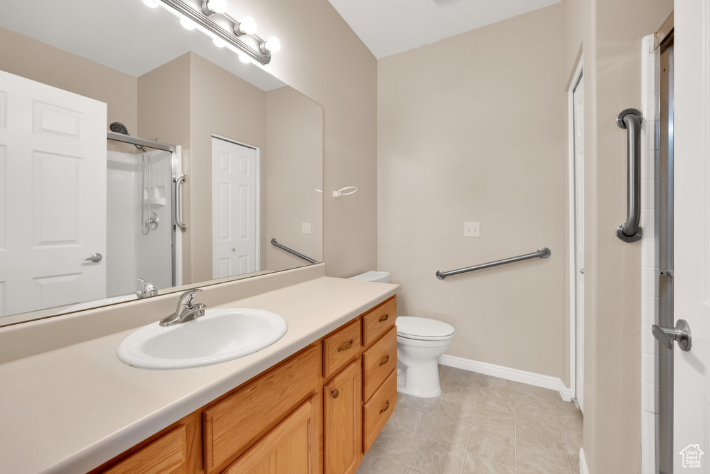 Bathroom featuring vanity, baseboards, a shower with door, and toilet