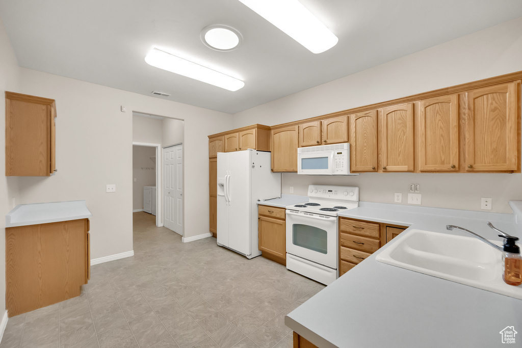 Kitchen with a sink, light floors, white appliances, and light countertops