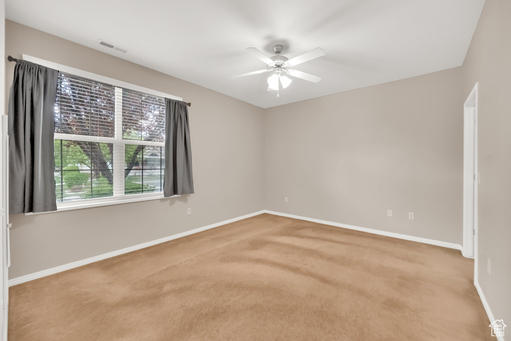 Carpeted empty room featuring baseboards, a ceiling fan, and visible vents