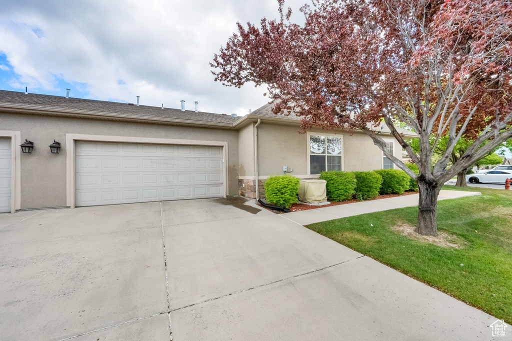 View of front of house featuring concrete driveway, an attached garage, a front yard, and stucco siding