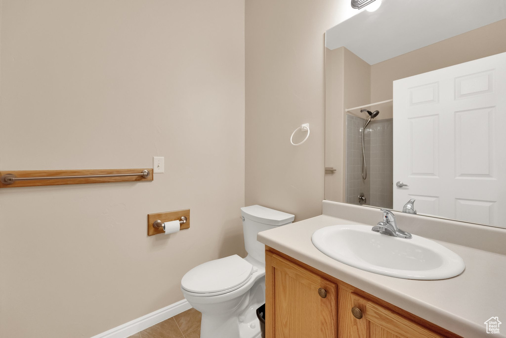 Bathroom featuring vanity, toilet, tile patterned floors, baseboards, and a shower