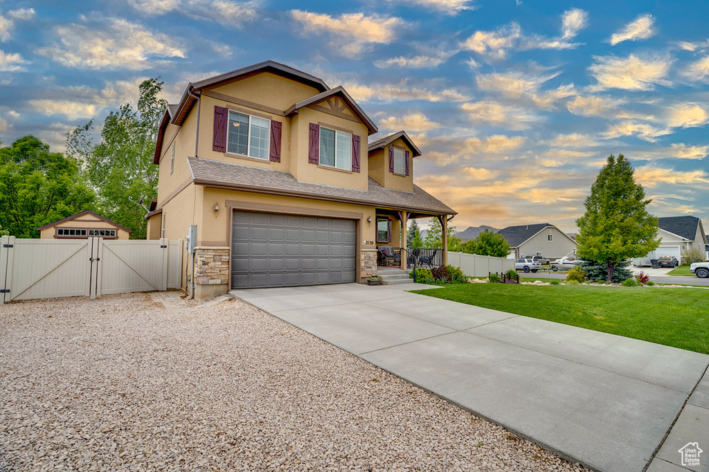 View of front facade with a gate, a garage, a front lawn, concrete driveway, and stucco siding