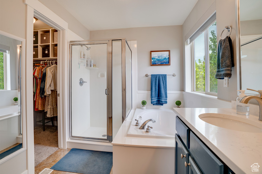 Full bath with vanity, a wealth of natural light, a garden tub, and a stall shower