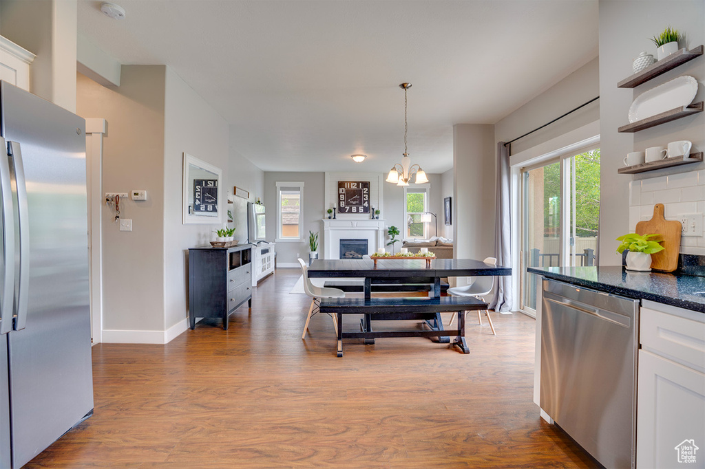 Kitchen featuring an inviting chandelier, white cabinetry, appliances with stainless steel finishes, and wood finished floors