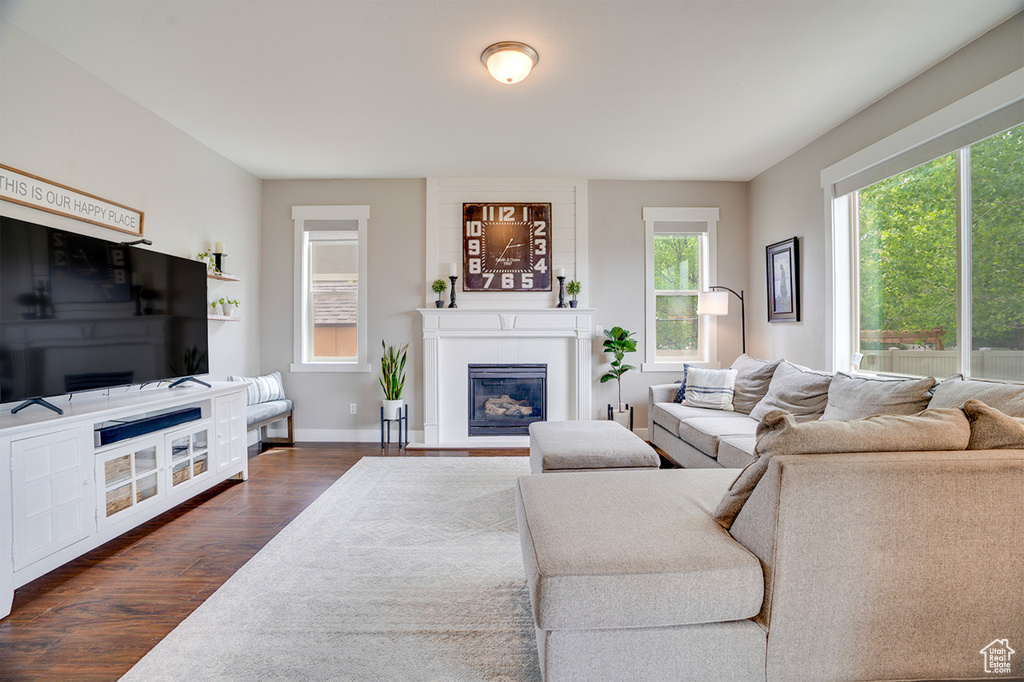 Living room with dark wood-type flooring, baseboards, and a glass covered fireplace
