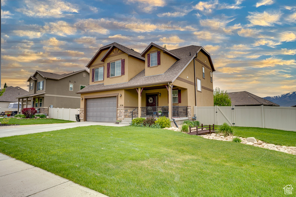 Craftsman house with fence, an attached garage, stone siding, stucco siding, and driveway