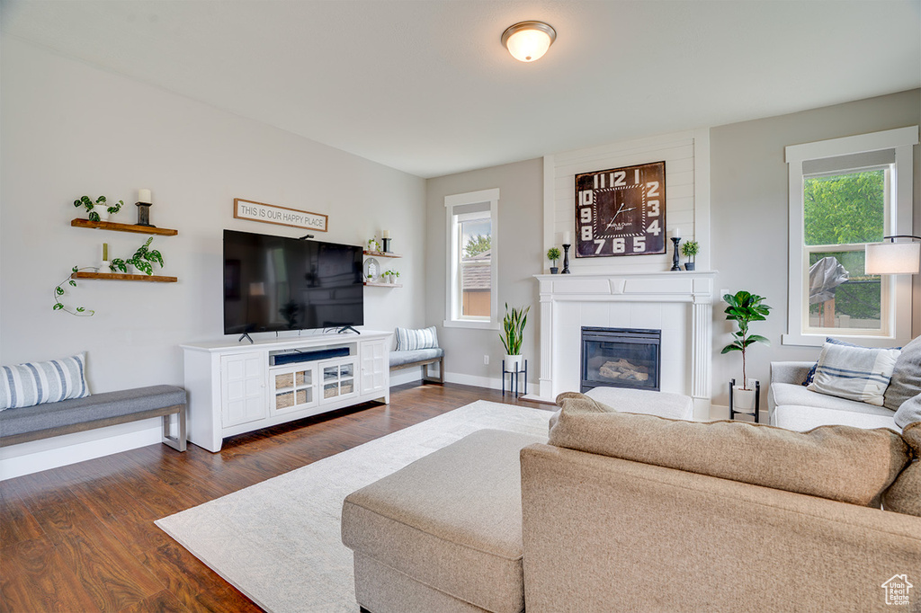 Living area with a glass covered fireplace, baseboards, and dark wood-style flooring