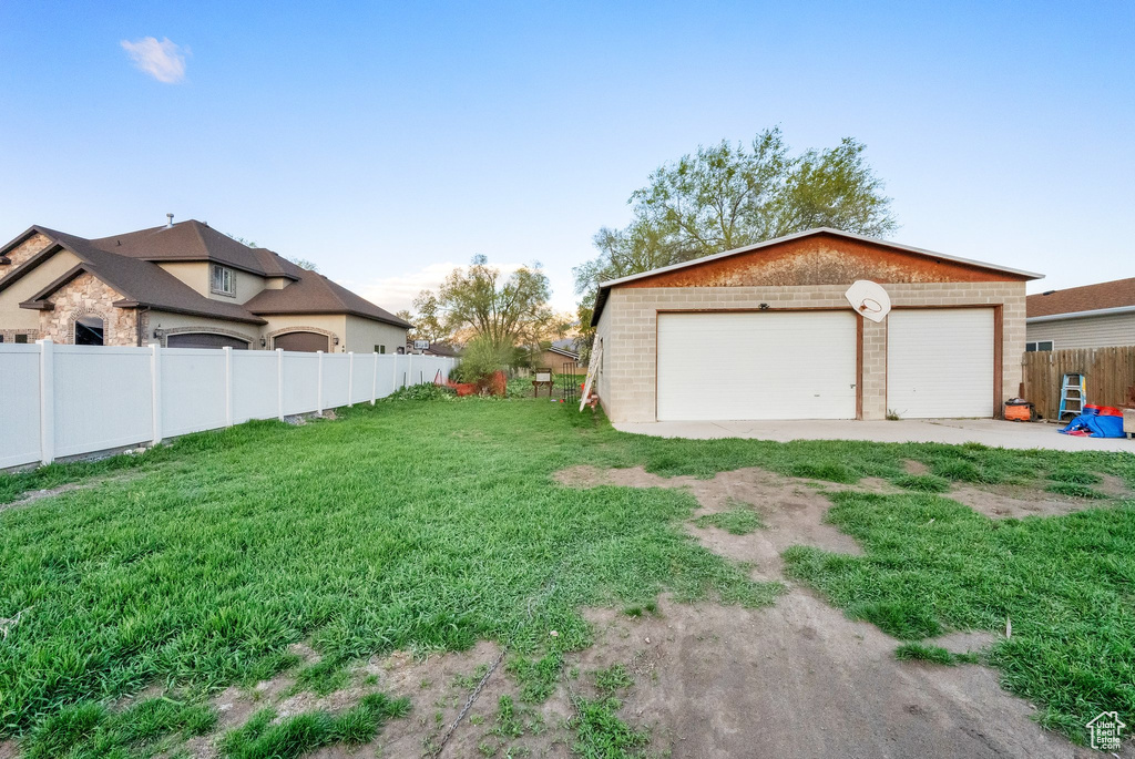 View of yard featuring fence, a detached garage, and an outdoor structure