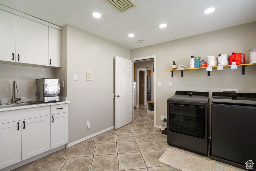 Washroom featuring washing machine and clothes dryer, recessed lighting, a sink, and cabinet space