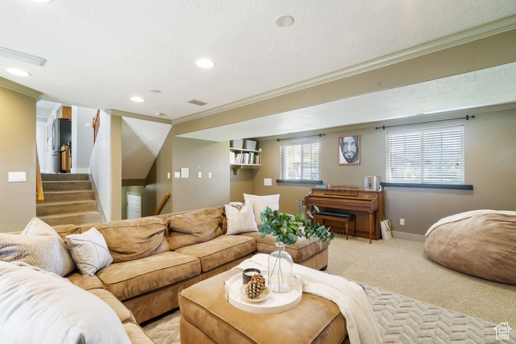 Living area with a textured ceiling, baseboards, ornamental molding, light carpet, and recessed lighting