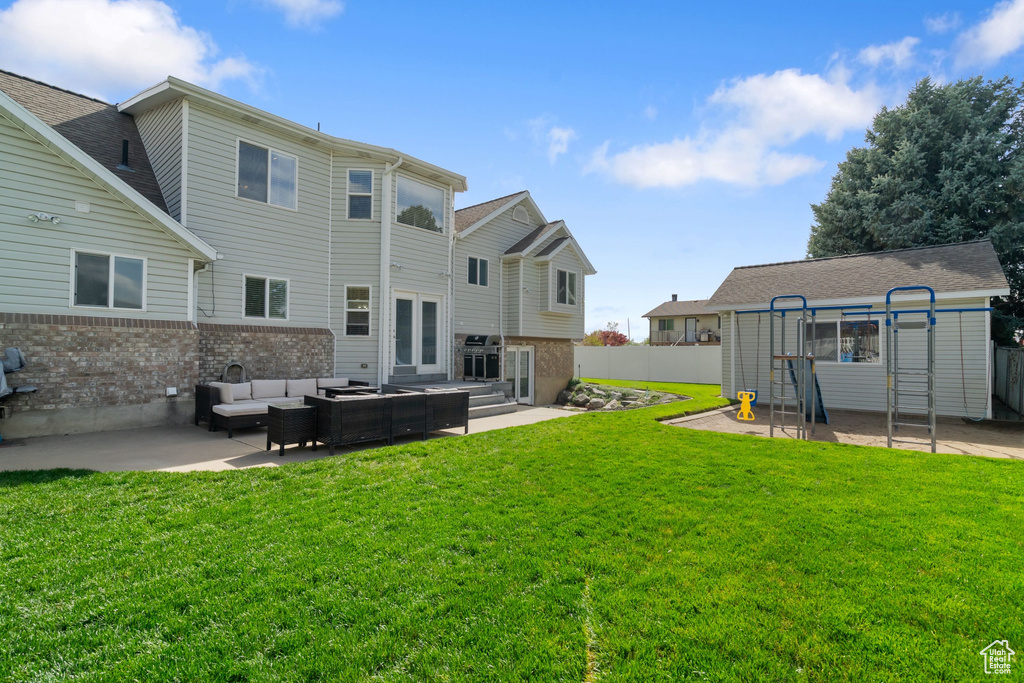 Rear view of property with an outdoor living space, a lawn, brick siding, and a patio
