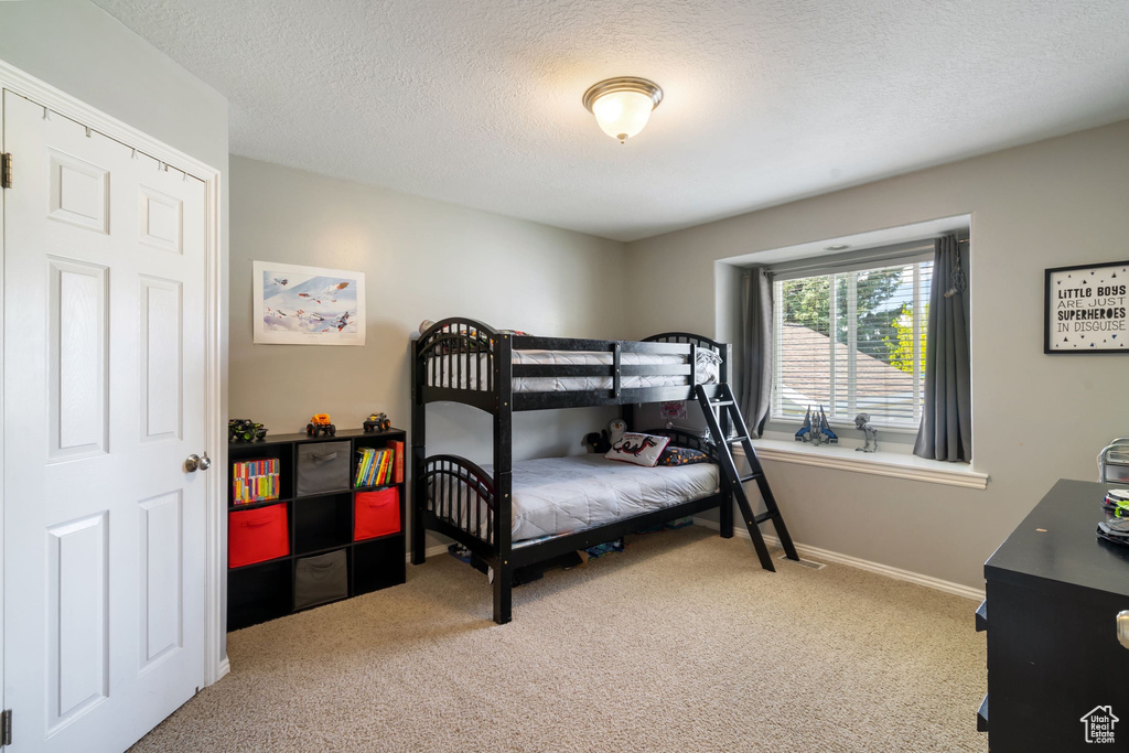 Bedroom with carpet flooring, a textured ceiling, and baseboards