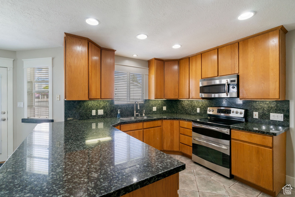 Kitchen featuring a sink, decorative backsplash, brown cabinets, and stainless steel appliances