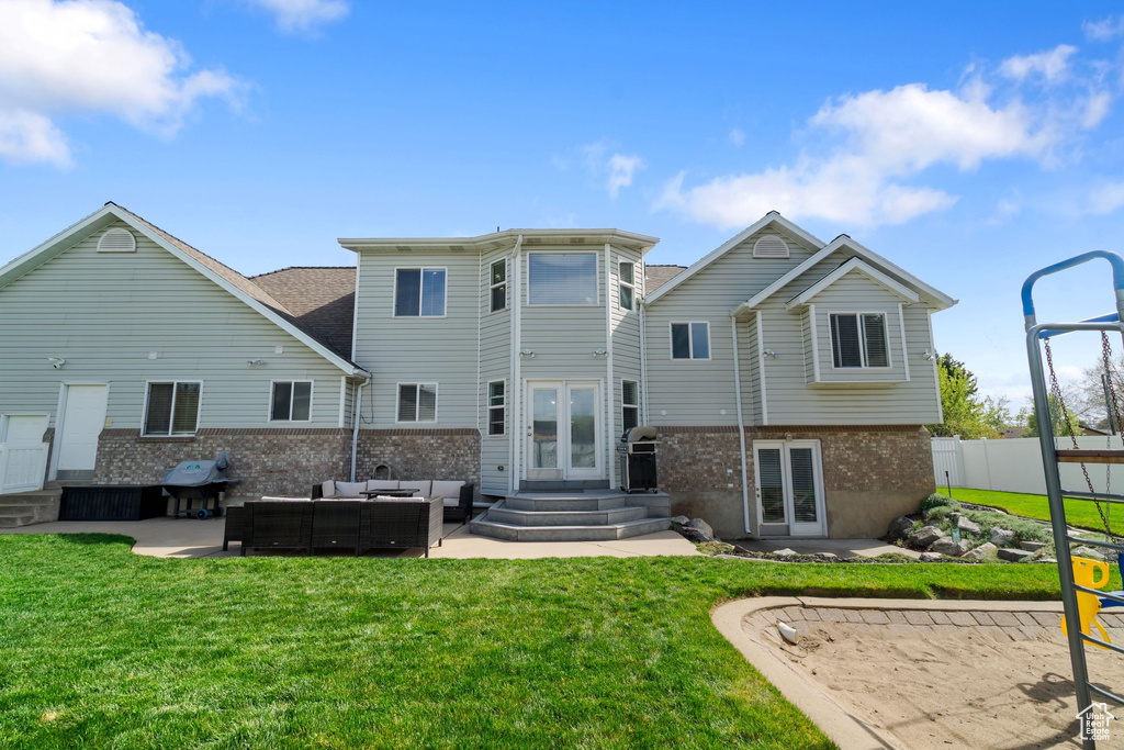 Rear view of property with french doors, an outdoor hangout area, brick siding, entry steps, and a lawn