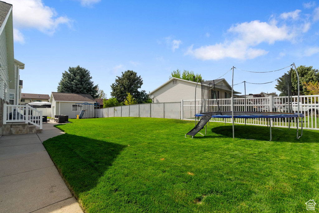 View of yard with central AC, a fenced backyard, and a trampoline