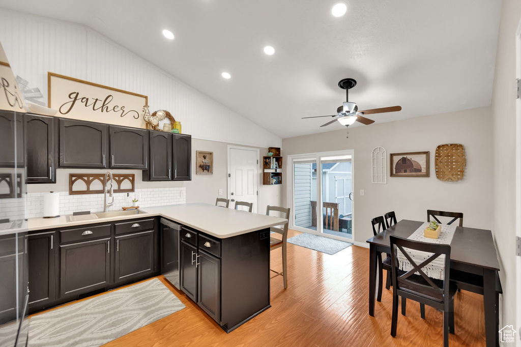Kitchen featuring dishwasher, a peninsula, a ceiling fan, light wood-type flooring, and vaulted ceiling
