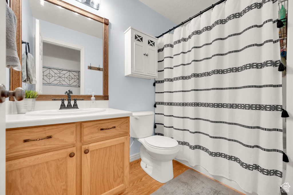 Full bathroom featuring toilet, a shower with curtain, wood finished floors, and vanity