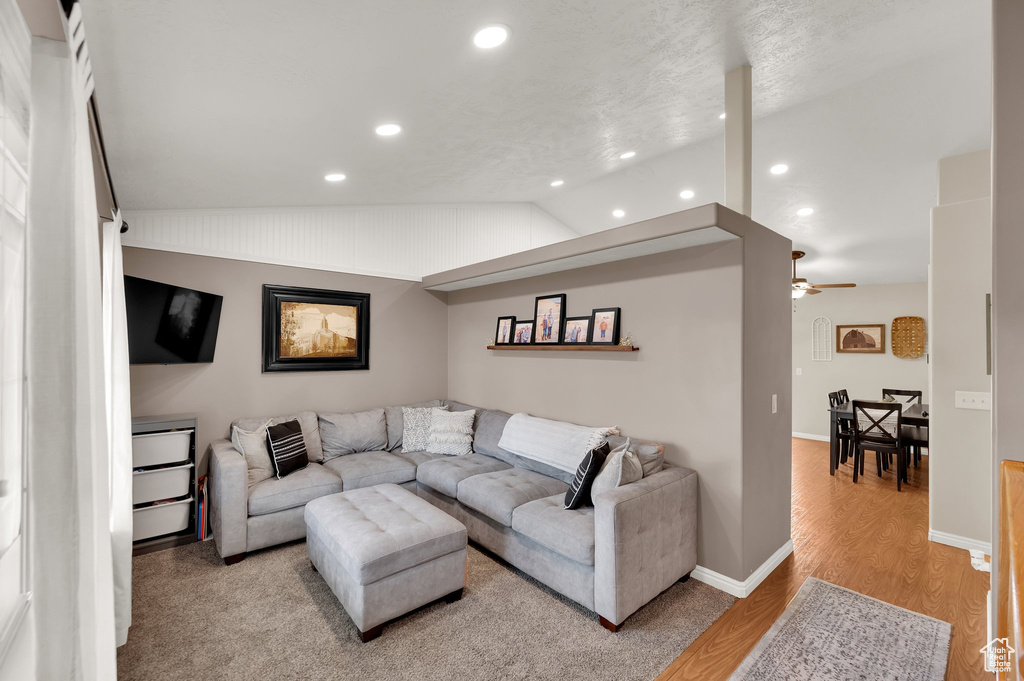 Living area with lofted ceiling, baseboards, recessed lighting, a ceiling fan, and light wood-style flooring
