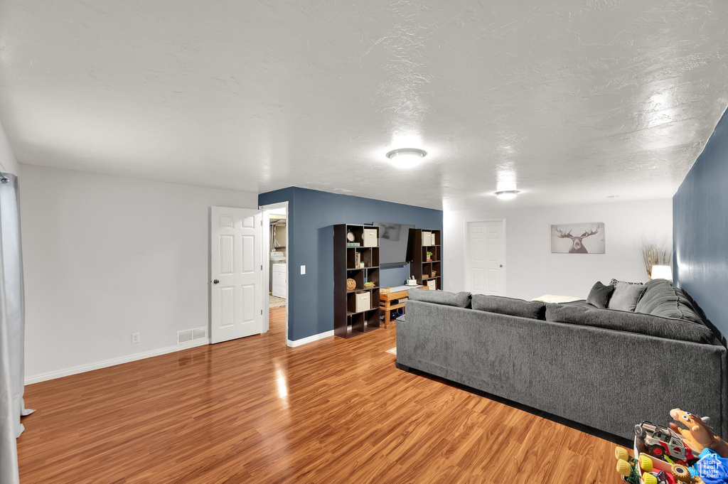 Living room featuring baseboards, washer / clothes dryer, wood finished floors, and visible vents