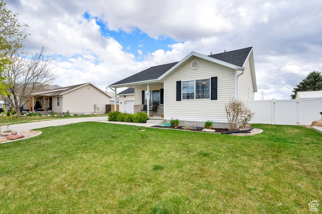 Ranch-style home featuring driveway, fence, a gate, and a front yard