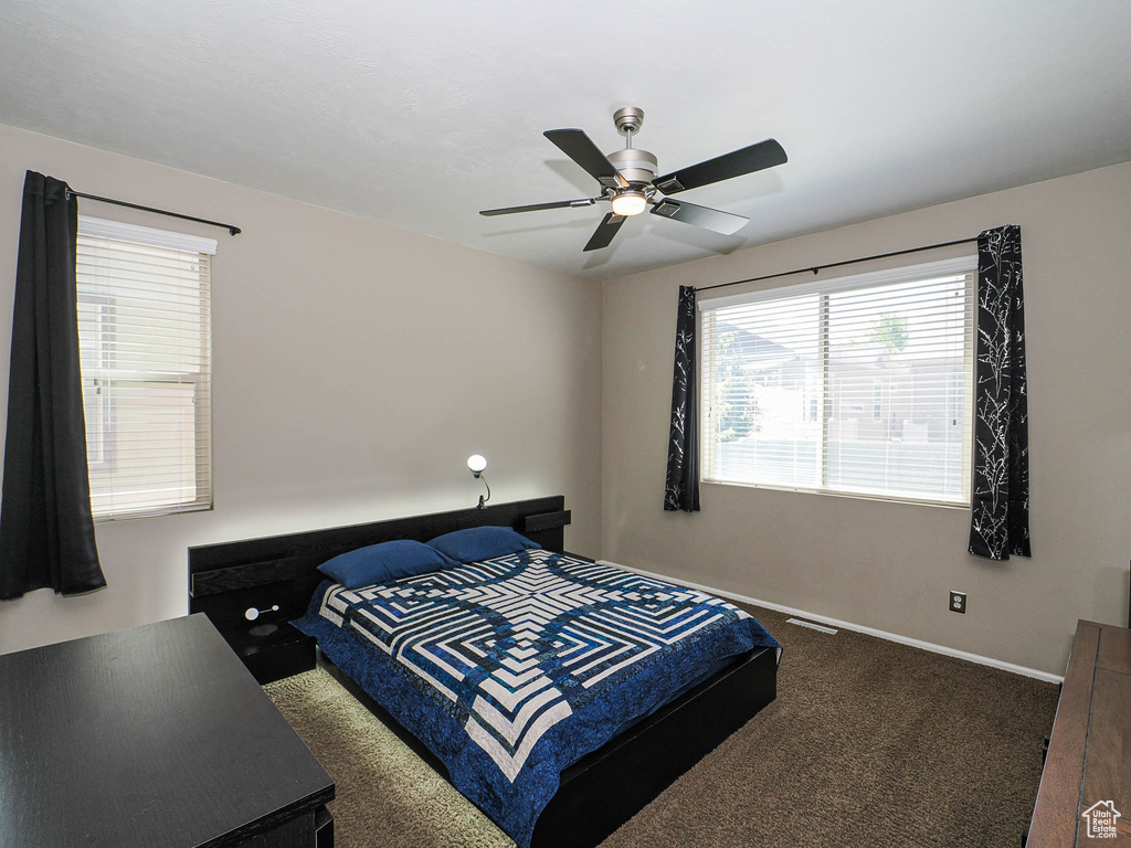 Carpeted bedroom with baseboards, a ceiling fan, and multiple windows