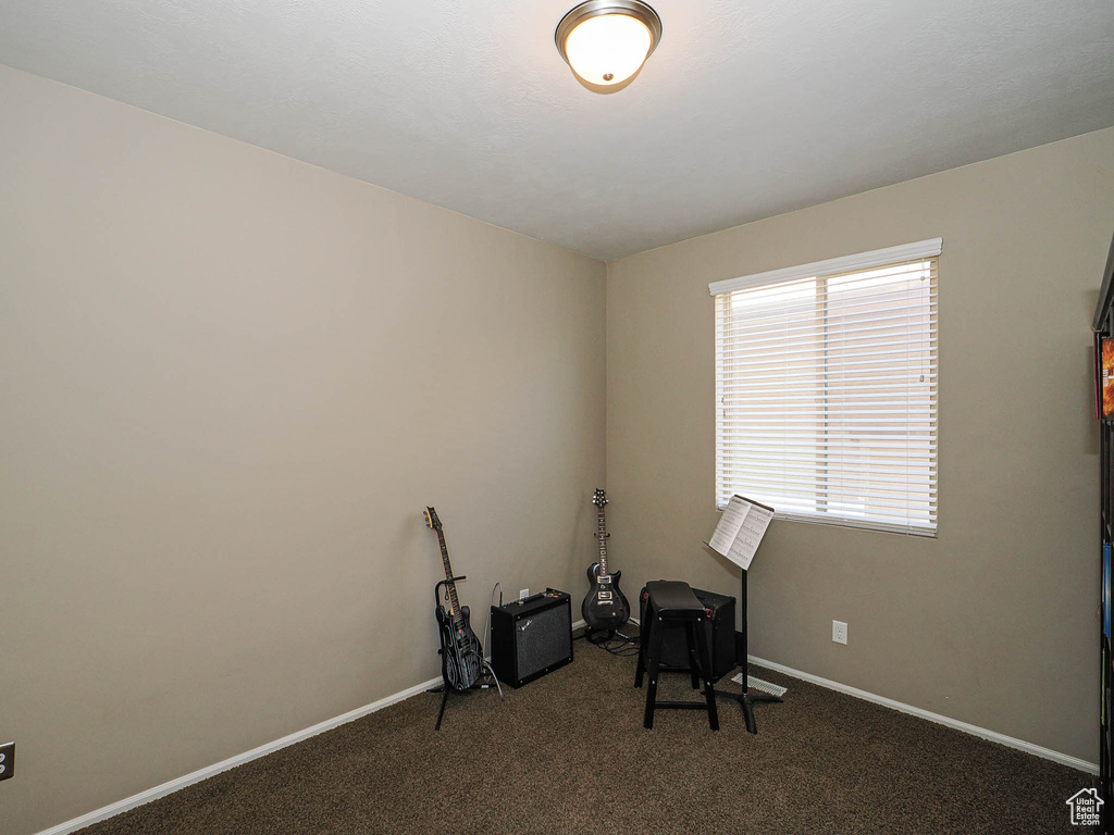 Misc room featuring baseboards and dark colored carpet