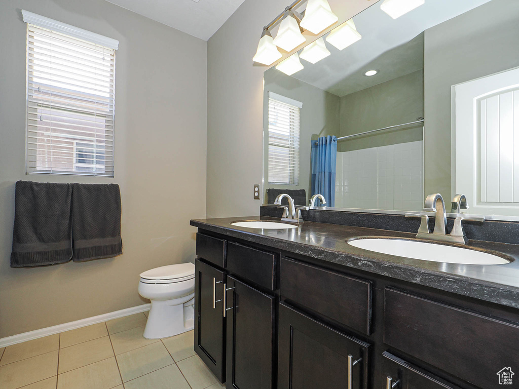 Bathroom featuring a sink, baseboards, tile patterned flooring, and toilet