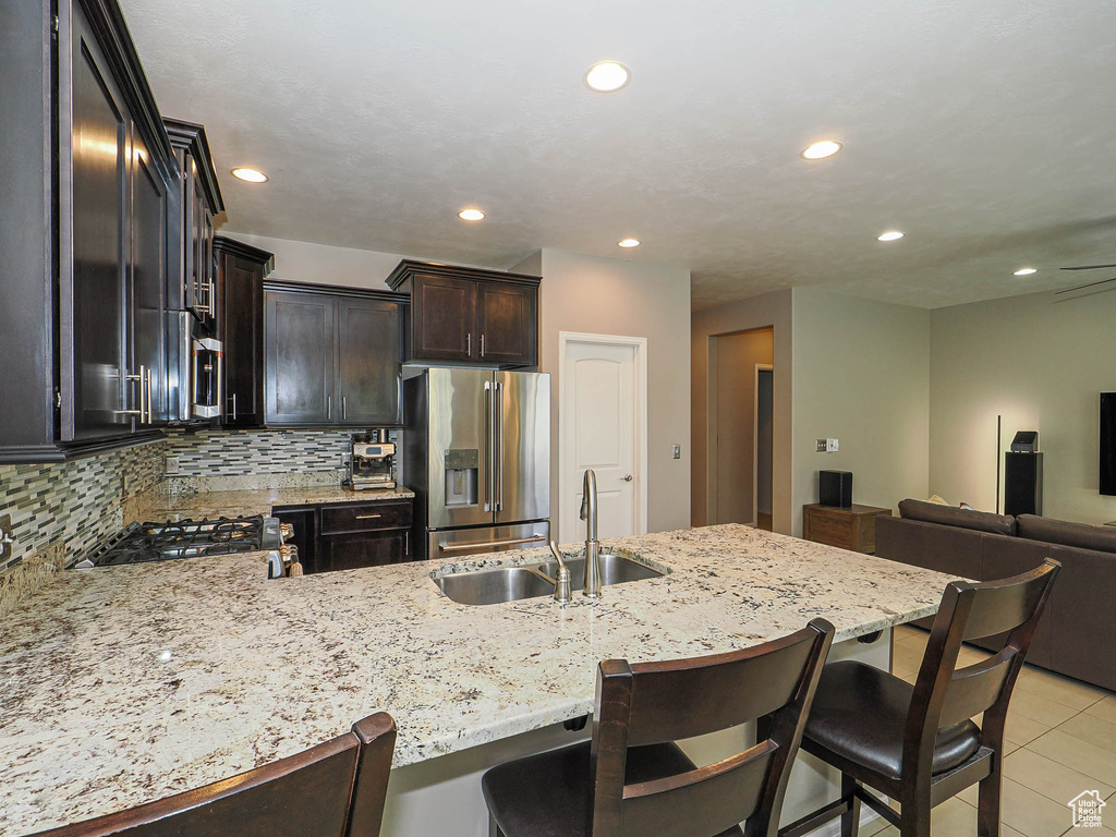 Kitchen with a peninsula, high end fridge, open floor plan, recessed lighting, and a sink