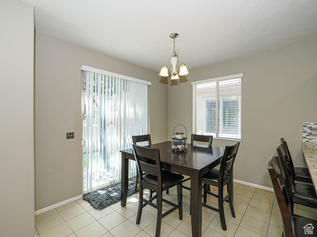 Dining area with baseboards, light tile patterned floors, and a chandelier