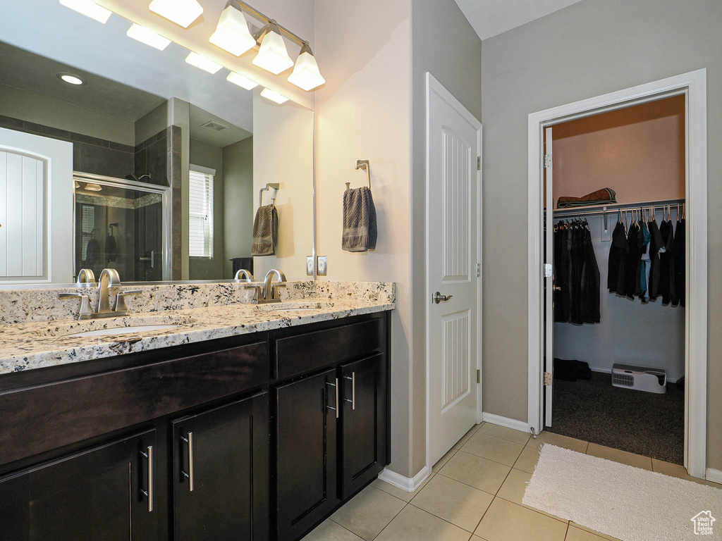 Full bathroom featuring double vanity, a sink, tile patterned floors, and a shower stall