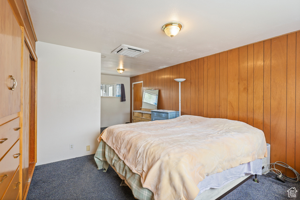 Carpeted bedroom featuring visible vents and wood walls