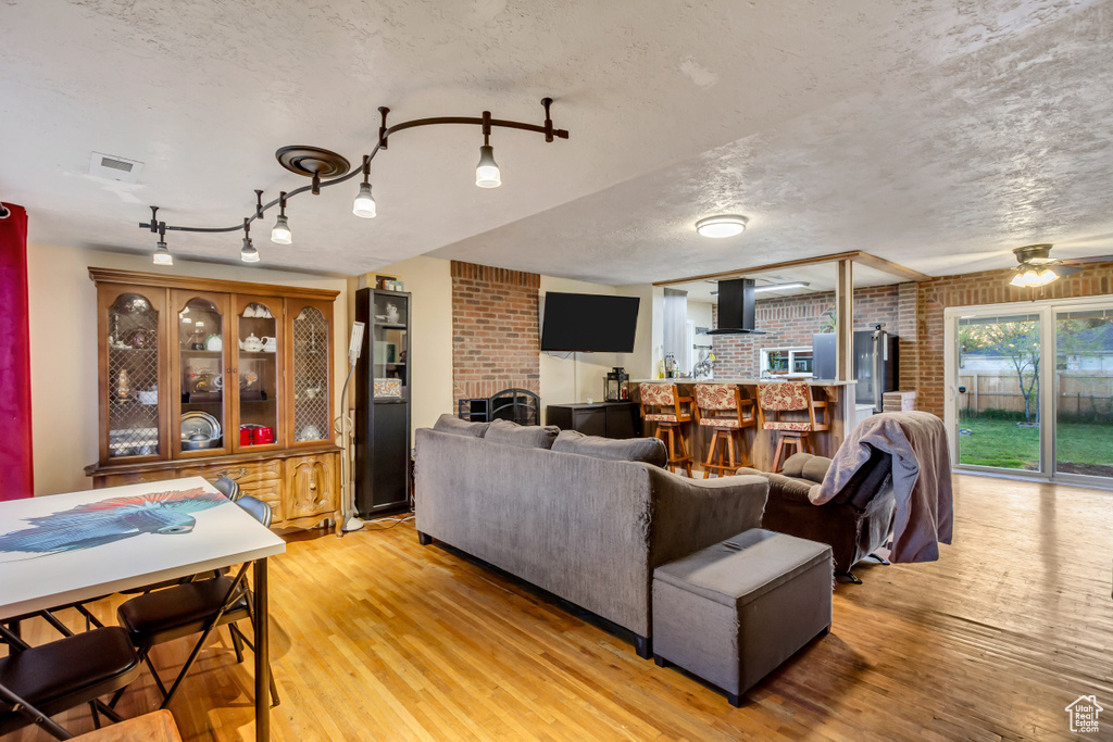 Living room with light wood-style floors, a textured ceiling, and brick wall