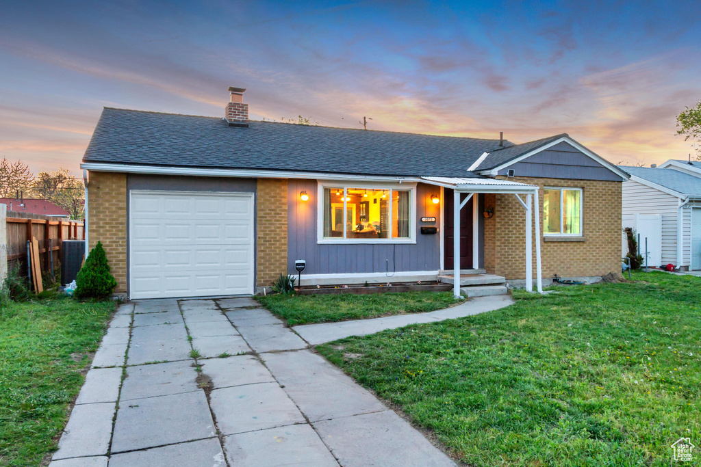 Ranch-style house with driveway, a chimney, brick siding, fence, and a yard