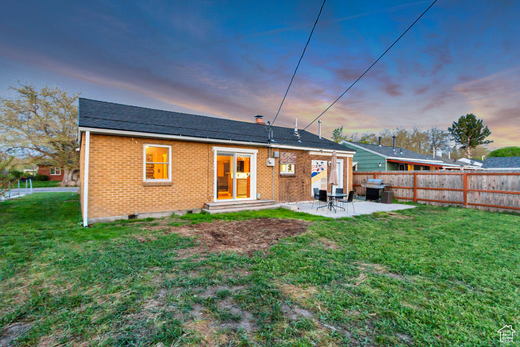 Back of house with fence, a patio, brick siding, entry steps, and a lawn