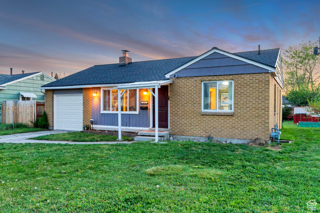 Ranch-style home with a chimney, a lawn, brick siding, fence, and an attached garage