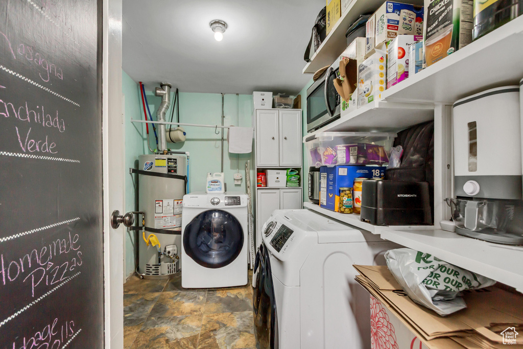 Washroom featuring cabinet space, washer and dryer, stone finish floor, and secured water heater
