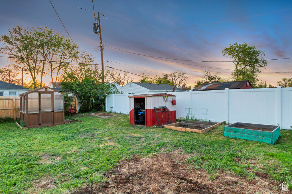 View of yard with an exterior structure, fence, an outbuilding, and a vegetable garden