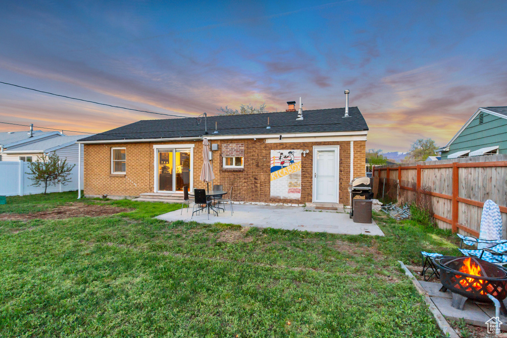 Rear view of house featuring a fenced backyard, entry steps, a yard, and a fire pit