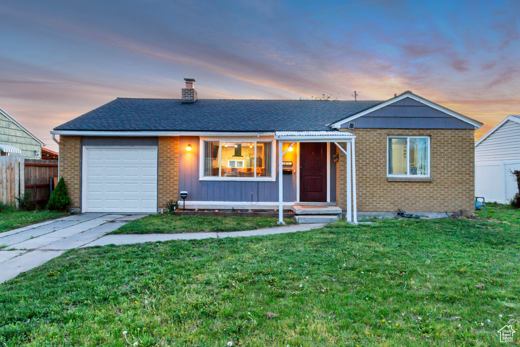 Ranch-style home featuring a garage, fence, a chimney, brick siding, and driveway