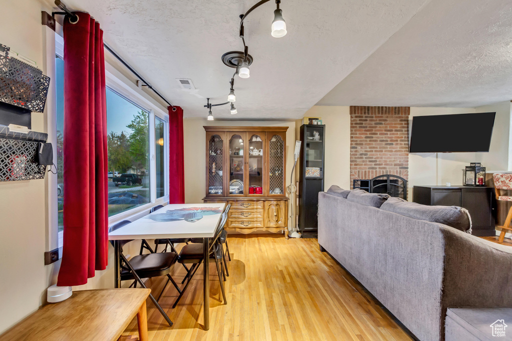 Interior space featuring track lighting, light wood finished floors, a fireplace, a textured ceiling, and visible vents