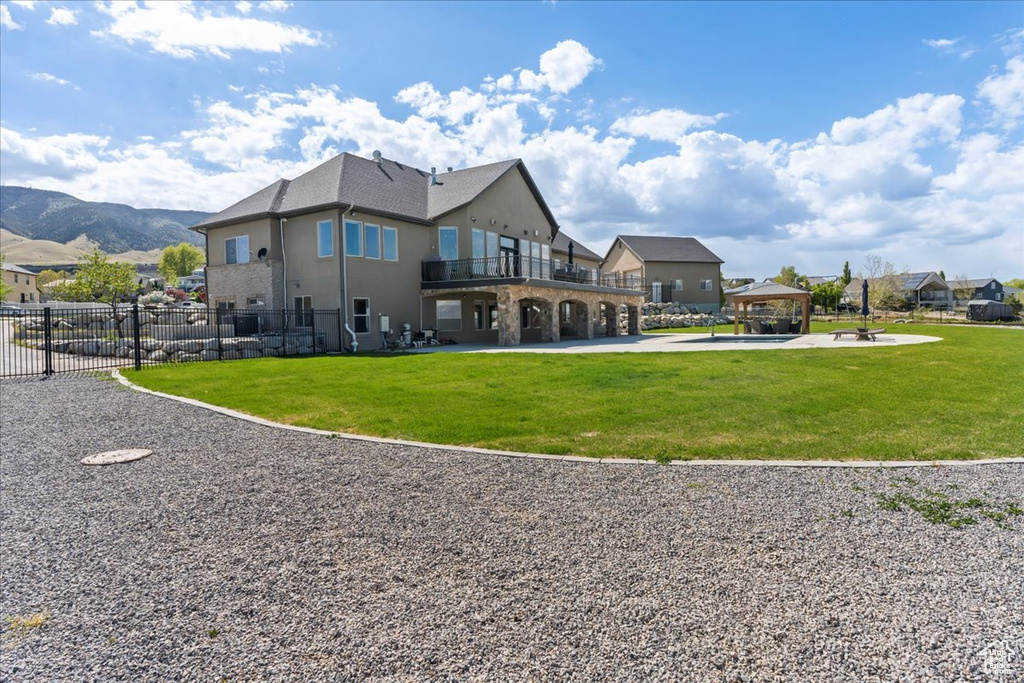 Back of property featuring a yard, a gazebo, fence, and stucco siding